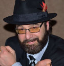 Middle aged man with a beard, wearing a hat and glasses.