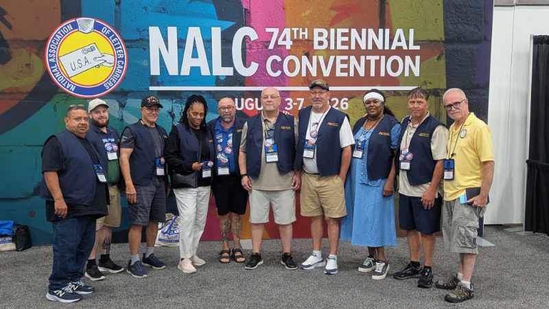 2026-nalc-convention Attendees of 2026 NALC Convention standing in fornt of giant wall banner.